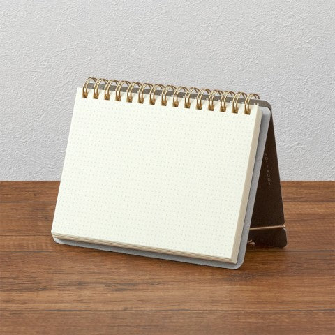 Small spiral-bound notebook on a wooden surface with a white background