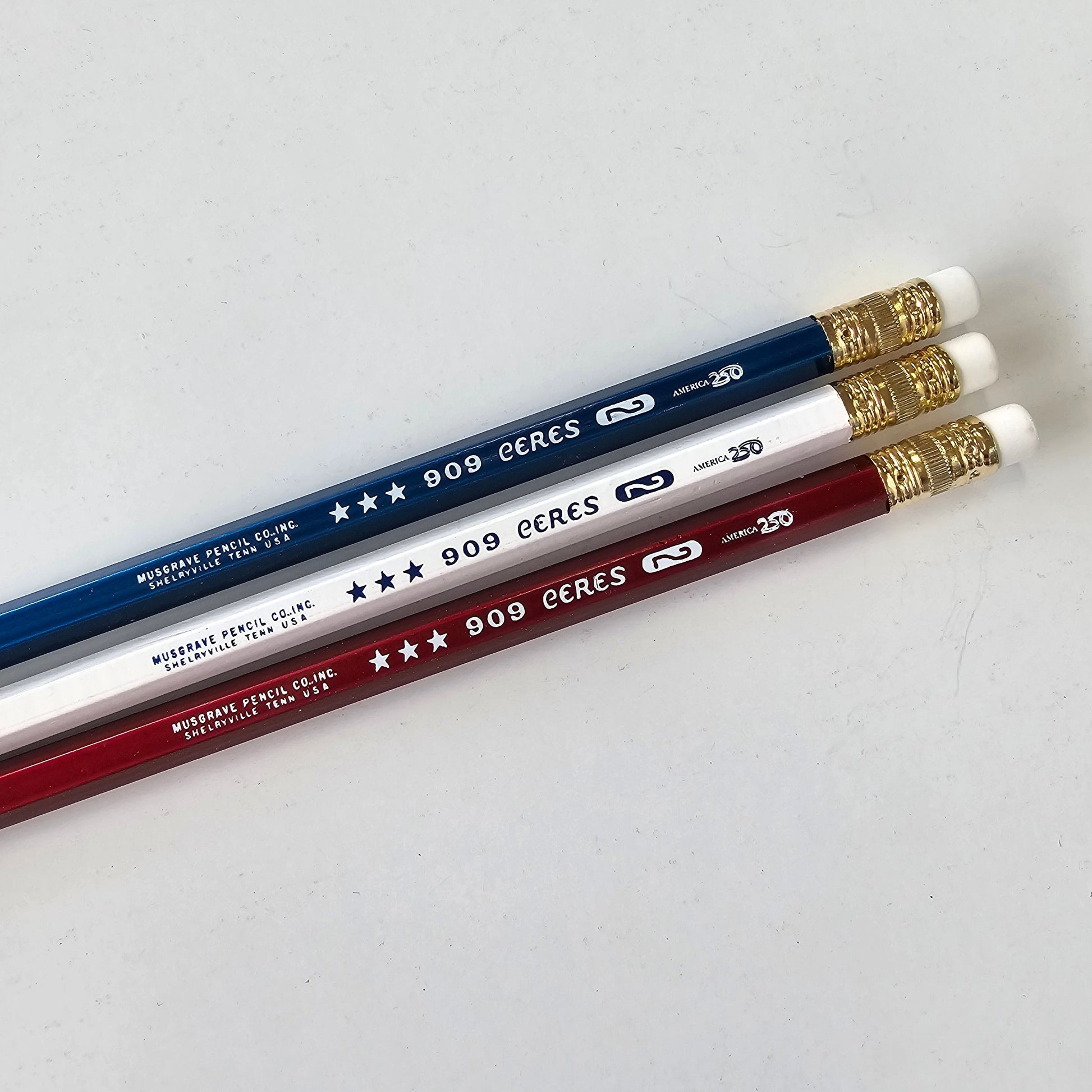 Three pencils in blue, white, and red on a light gray background